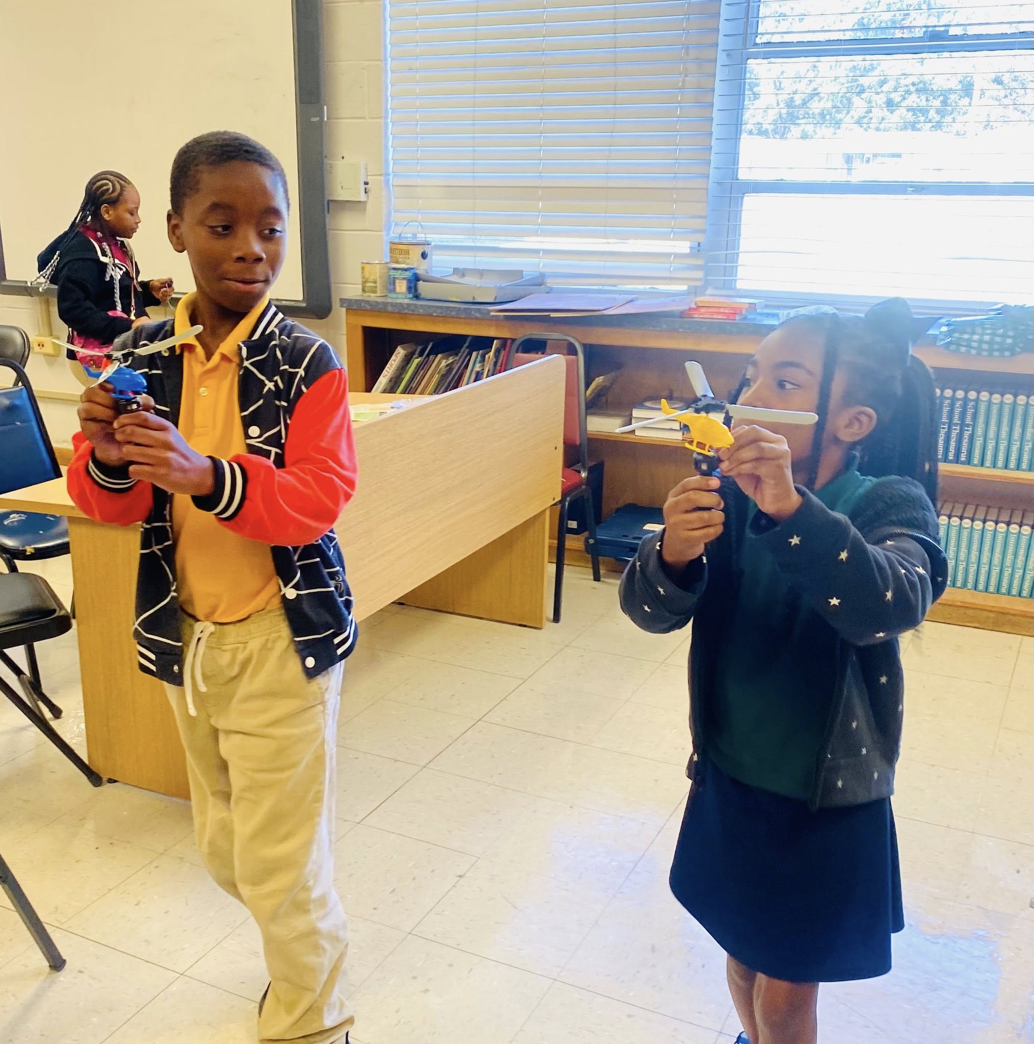 A boy and a girl holding toy helicopters.